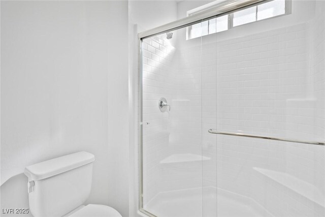 bathroom with toilet and an enclosed shower