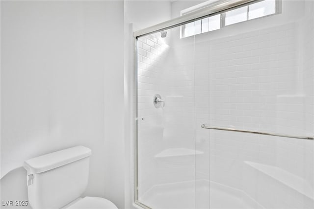 bathroom featuring toilet and a shower with door