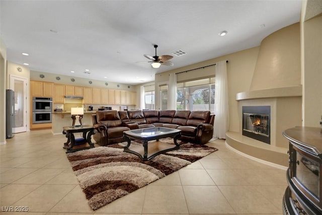 tiled living room with a large fireplace and ceiling fan