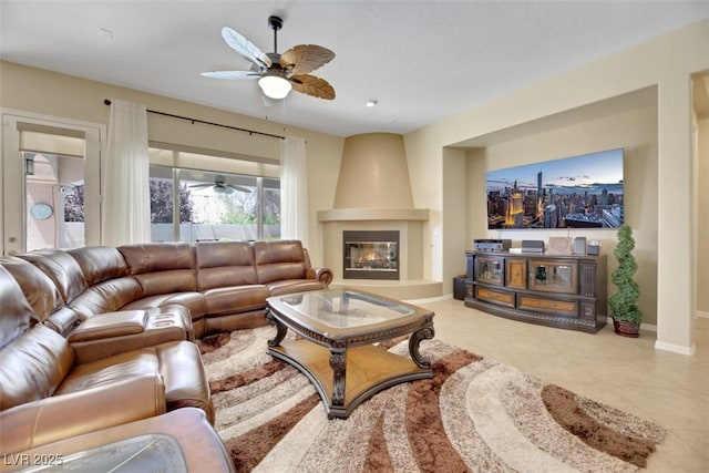 tiled living room with ceiling fan and a fireplace