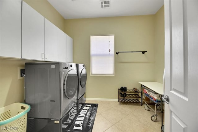 laundry room with light tile patterned floors, washer and clothes dryer, and cabinets