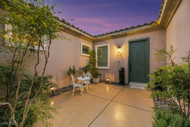 exterior entry at dusk featuring a patio