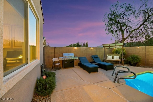 patio terrace at dusk with a fenced in pool