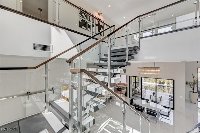 staircase featuring a towering ceiling and visible vents