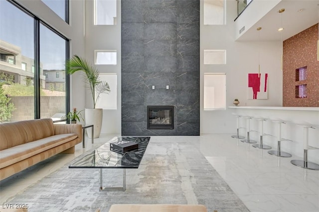 living room featuring marble finish floor, a high end fireplace, and a towering ceiling