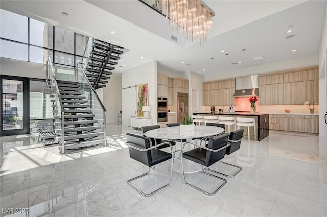 dining space with a chandelier, marble finish floor, a high ceiling, and stairs