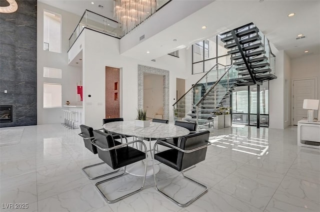 dining area featuring recessed lighting, visible vents, a towering ceiling, marble finish floor, and stairway