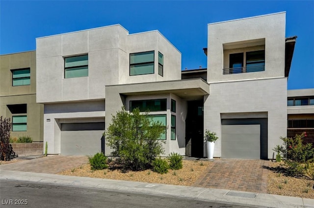 contemporary home with a garage, decorative driveway, and stucco siding