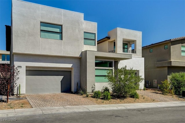 contemporary home featuring a garage, decorative driveway, and stucco siding