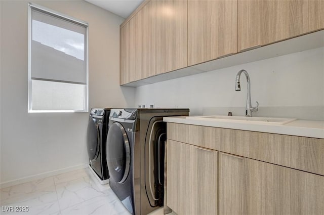 washroom featuring marble finish floor, washer and clothes dryer, cabinet space, a sink, and baseboards