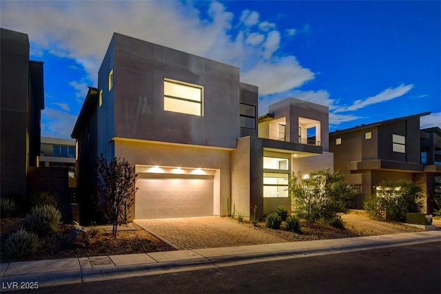 contemporary house featuring a garage, decorative driveway, and stucco siding