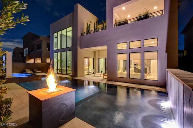 back of house with a patio area, a fire pit, and an in ground hot tub