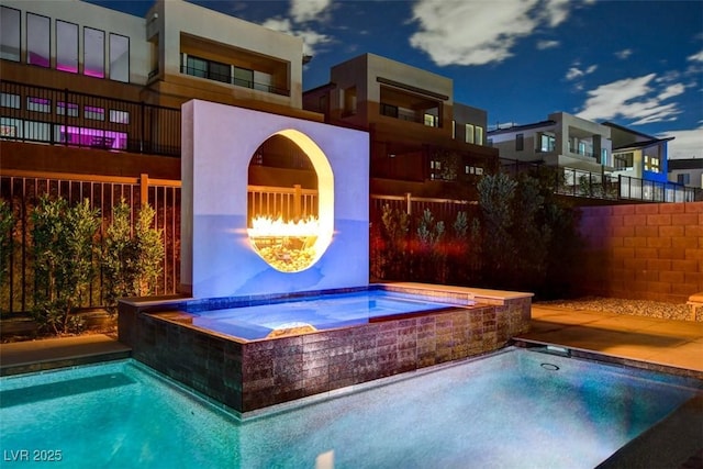 view of swimming pool featuring an in ground hot tub, a fireplace, and fence