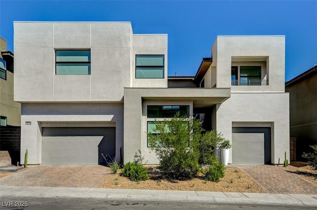 contemporary home with a garage, decorative driveway, and stucco siding