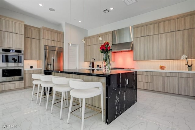 kitchen featuring an island with sink, wall chimney exhaust hood, modern cabinets, and appliances with stainless steel finishes