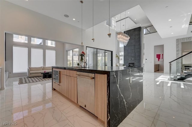 kitchen with marble finish floor, decorative light fixtures, a large island, open floor plan, and dark stone countertops