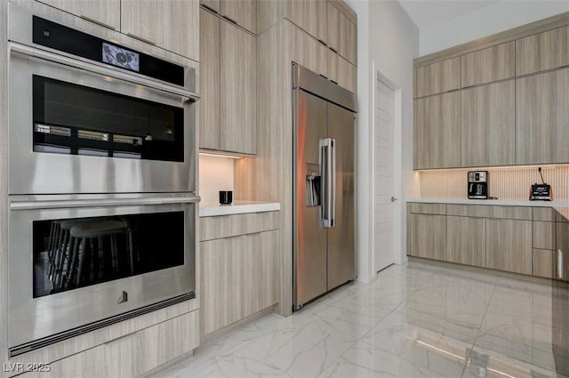 kitchen with light brown cabinets, marble finish floor, light countertops, appliances with stainless steel finishes, and modern cabinets