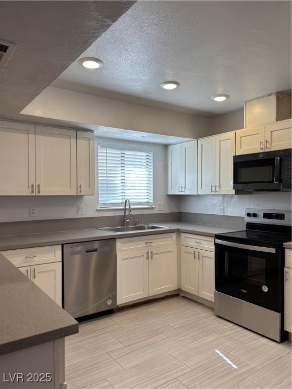 kitchen featuring white cabinetry, sink, stainless steel appliances, and a textured ceiling