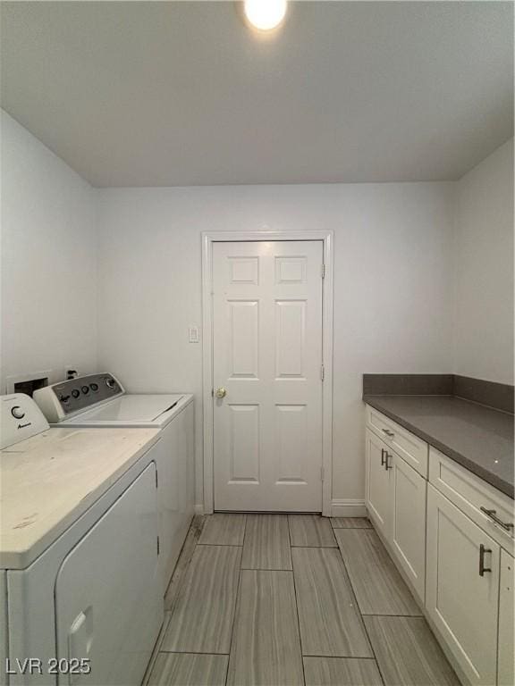 clothes washing area with cabinets and separate washer and dryer