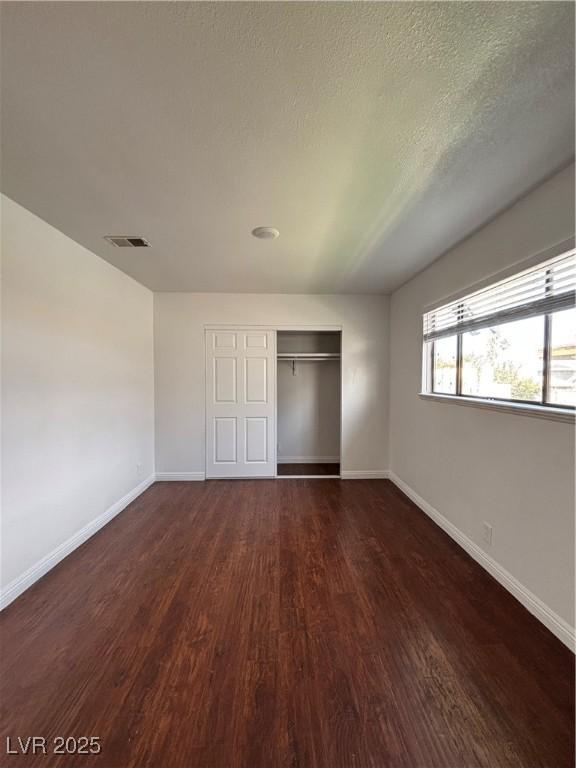 unfurnished bedroom featuring dark hardwood / wood-style floors, a textured ceiling, and a closet