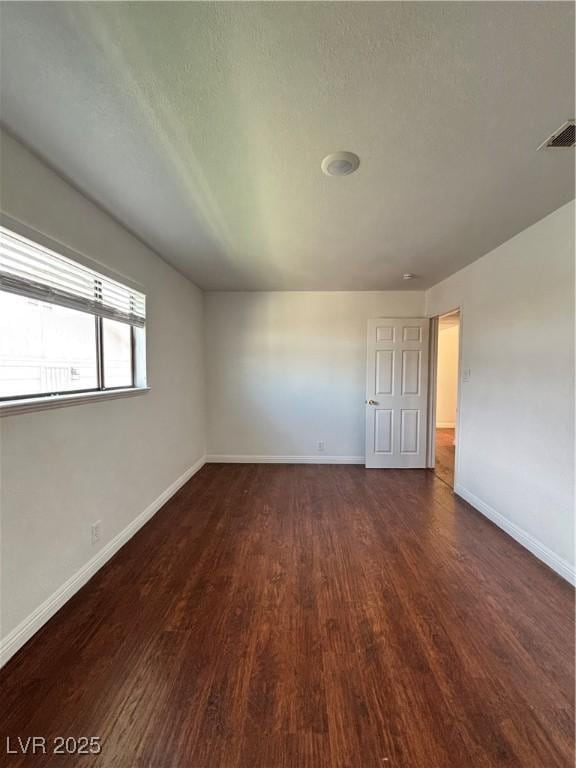 empty room featuring dark hardwood / wood-style flooring and a textured ceiling