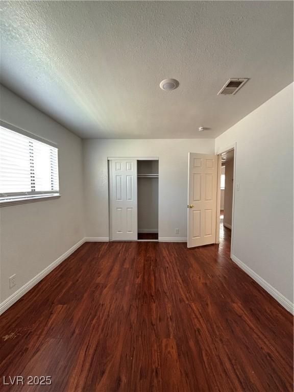 unfurnished bedroom featuring dark hardwood / wood-style floors, a closet, and a textured ceiling