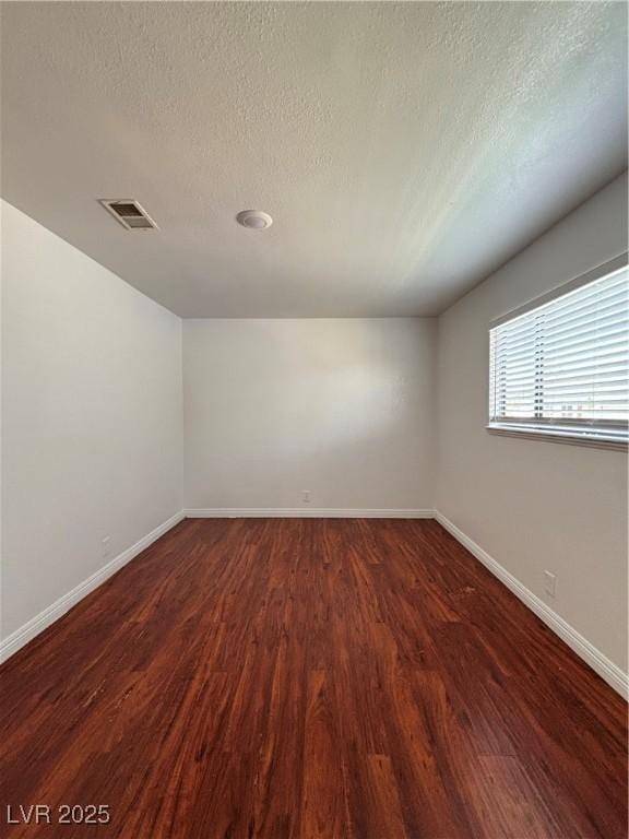 unfurnished room with dark hardwood / wood-style flooring and a textured ceiling