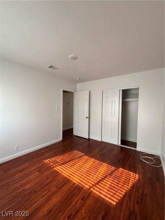 unfurnished bedroom with dark hardwood / wood-style flooring and a closet