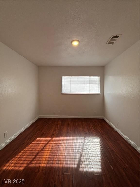 spare room featuring dark hardwood / wood-style flooring and a textured ceiling