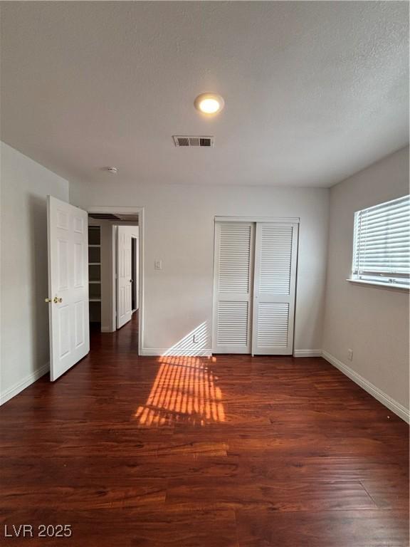 unfurnished bedroom featuring dark wood-type flooring, a closet, and a textured ceiling