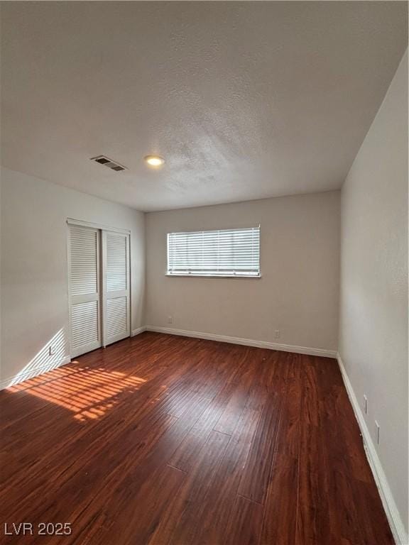 unfurnished bedroom featuring dark hardwood / wood-style flooring, a closet, and a textured ceiling