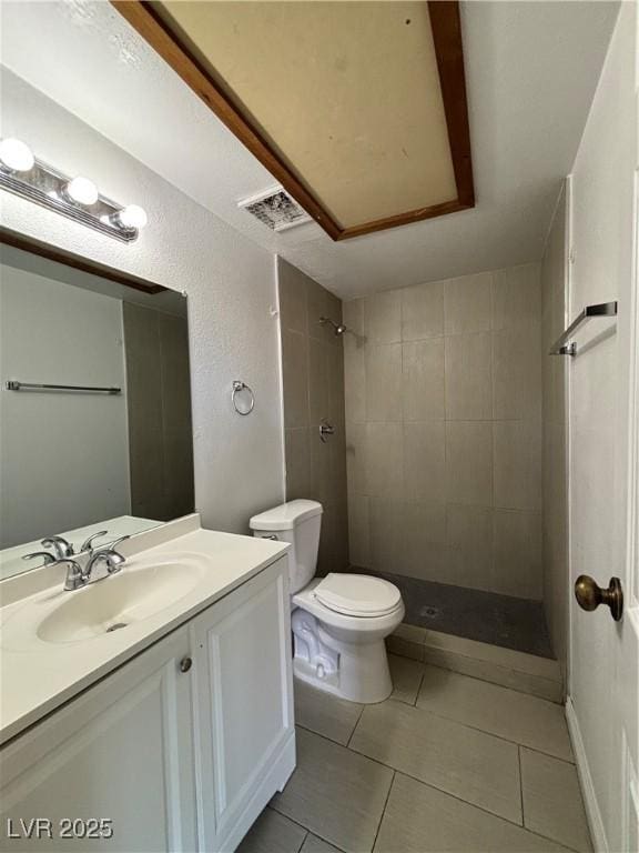 bathroom with vanity, tile patterned floors, toilet, and tiled shower