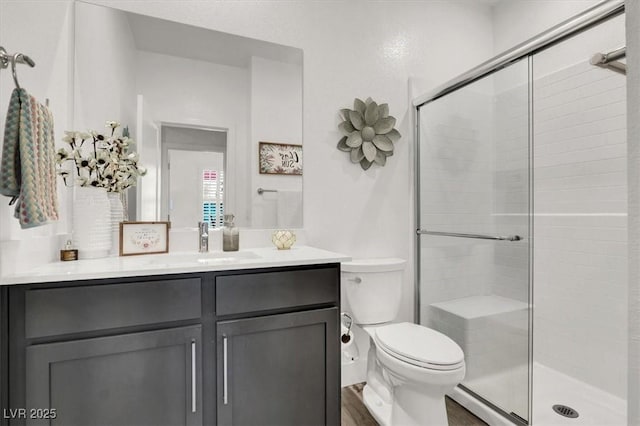 bathroom with vanity, toilet, a shower with shower door, and hardwood / wood-style floors