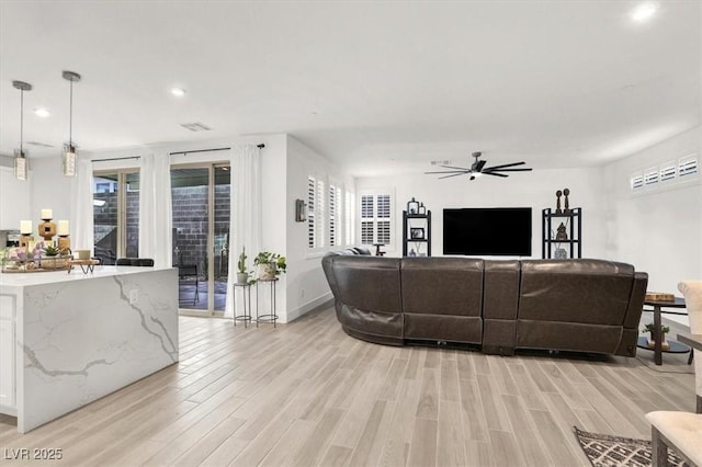 living room featuring ceiling fan and light hardwood / wood-style flooring