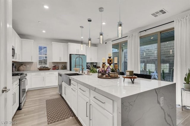 kitchen with stainless steel appliances, white cabinetry, a large island, and pendant lighting