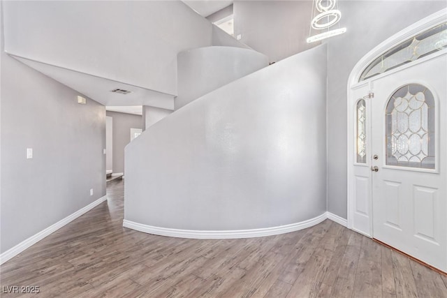 foyer entrance featuring a towering ceiling and hardwood / wood-style floors