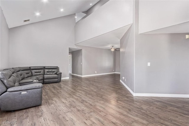 living room with hardwood / wood-style flooring, ceiling fan, and high vaulted ceiling