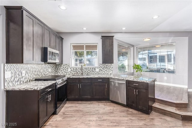 kitchen featuring sink, stainless steel appliances, light stone counters, tasteful backsplash, and light hardwood / wood-style floors