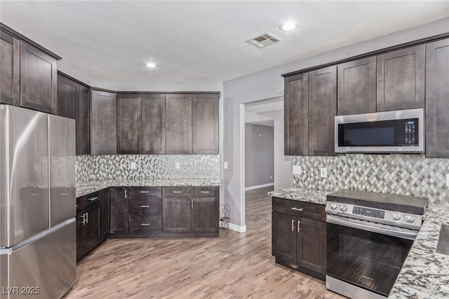 kitchen featuring tasteful backsplash, stainless steel appliances, light stone countertops, dark brown cabinets, and light wood-type flooring