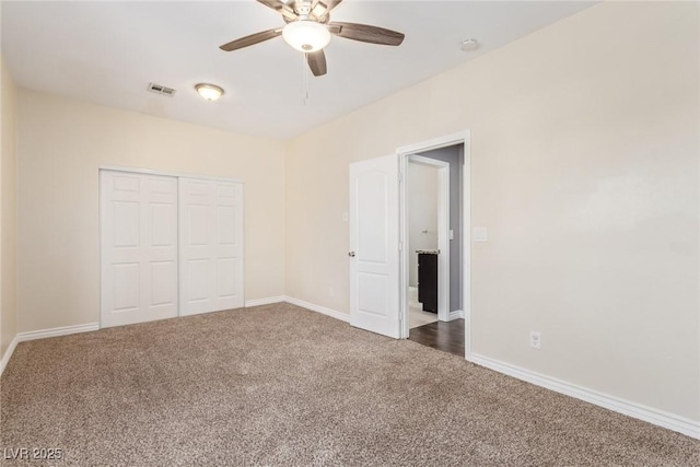 unfurnished bedroom with ceiling fan, dark carpet, and a closet