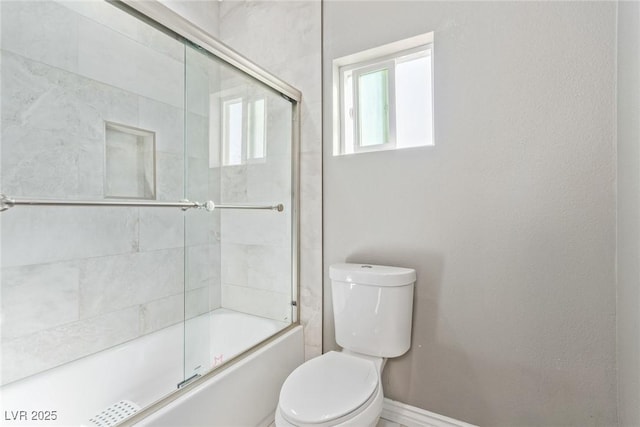 bathroom featuring enclosed tub / shower combo and toilet