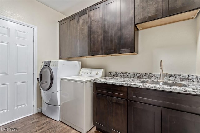 washroom with cabinets, wood-type flooring, sink, and independent washer and dryer