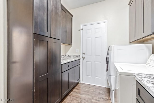 clothes washing area with independent washer and dryer, cabinets, and light wood-type flooring