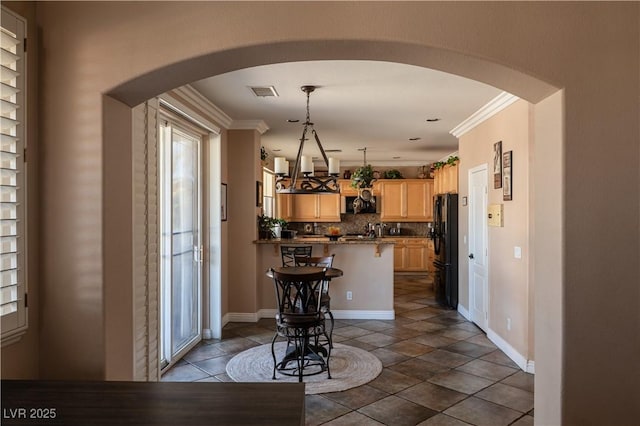 kitchen featuring black refrigerator, a breakfast bar, tasteful backsplash, kitchen peninsula, and light brown cabinets