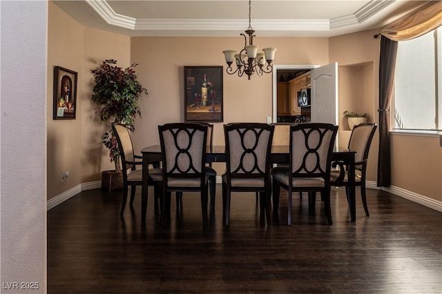 dining area with crown molding, dark wood-type flooring, an inviting chandelier, and a tray ceiling