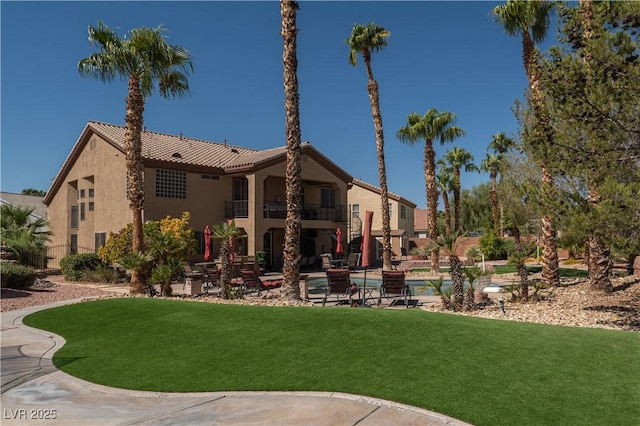 back of property with a balcony and a yard