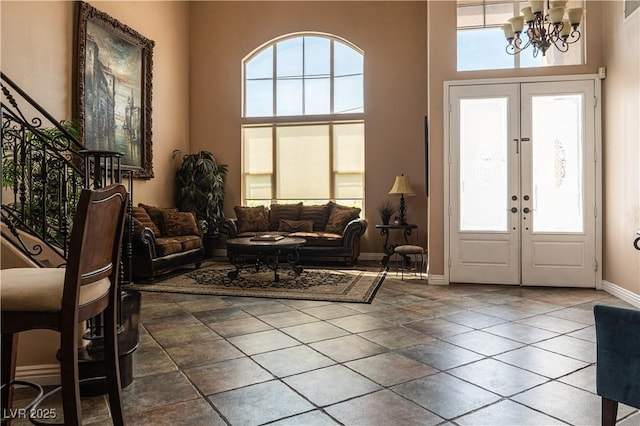 interior space with a towering ceiling, an inviting chandelier, and french doors