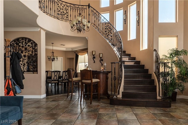 interior space featuring a high ceiling, ornamental molding, a healthy amount of sunlight, and an inviting chandelier