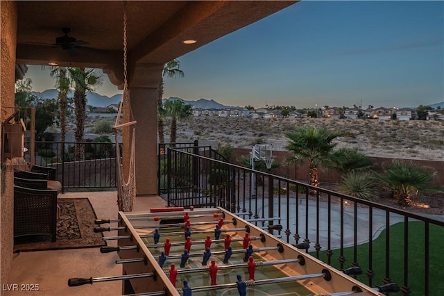 balcony at dusk with ceiling fan and a mountain view