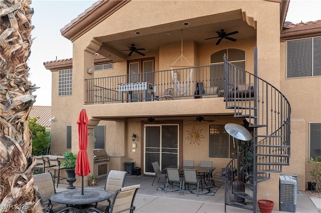 back of house with ceiling fan, a balcony, and a patio